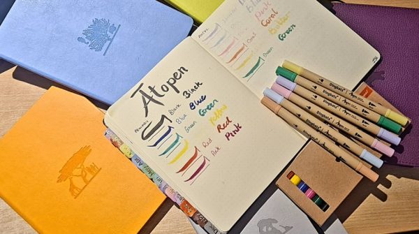 Selection of Dingbats* Notebooks, Journals and Ātopen Pens on a desk