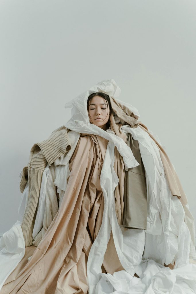 A woman almost completely covered in a pike of clothes
