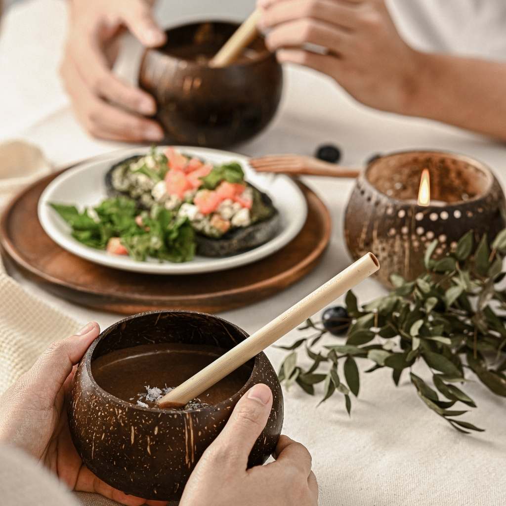Coconut shell cups being used with bamboo straws, at a picnic table.