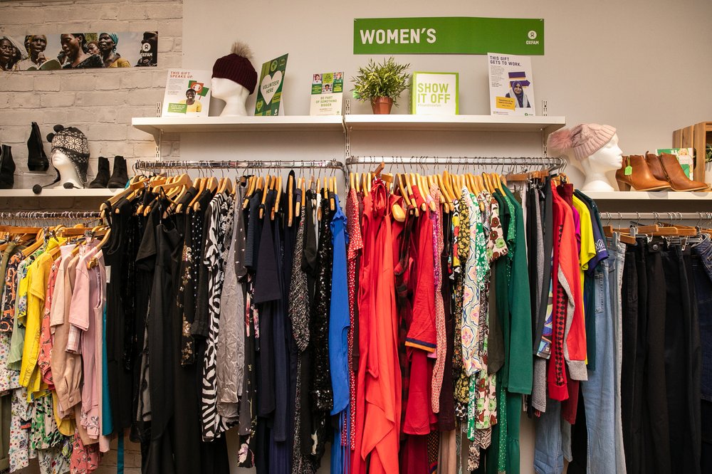 Clothing items for sale, displayed on a rail, in and Oxfam Shop, UK.