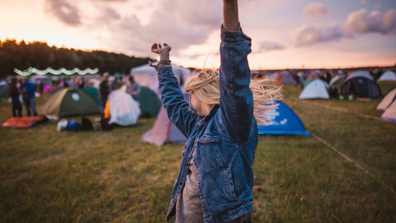 A woman enjoying a music festival, dancing amongst the tents.