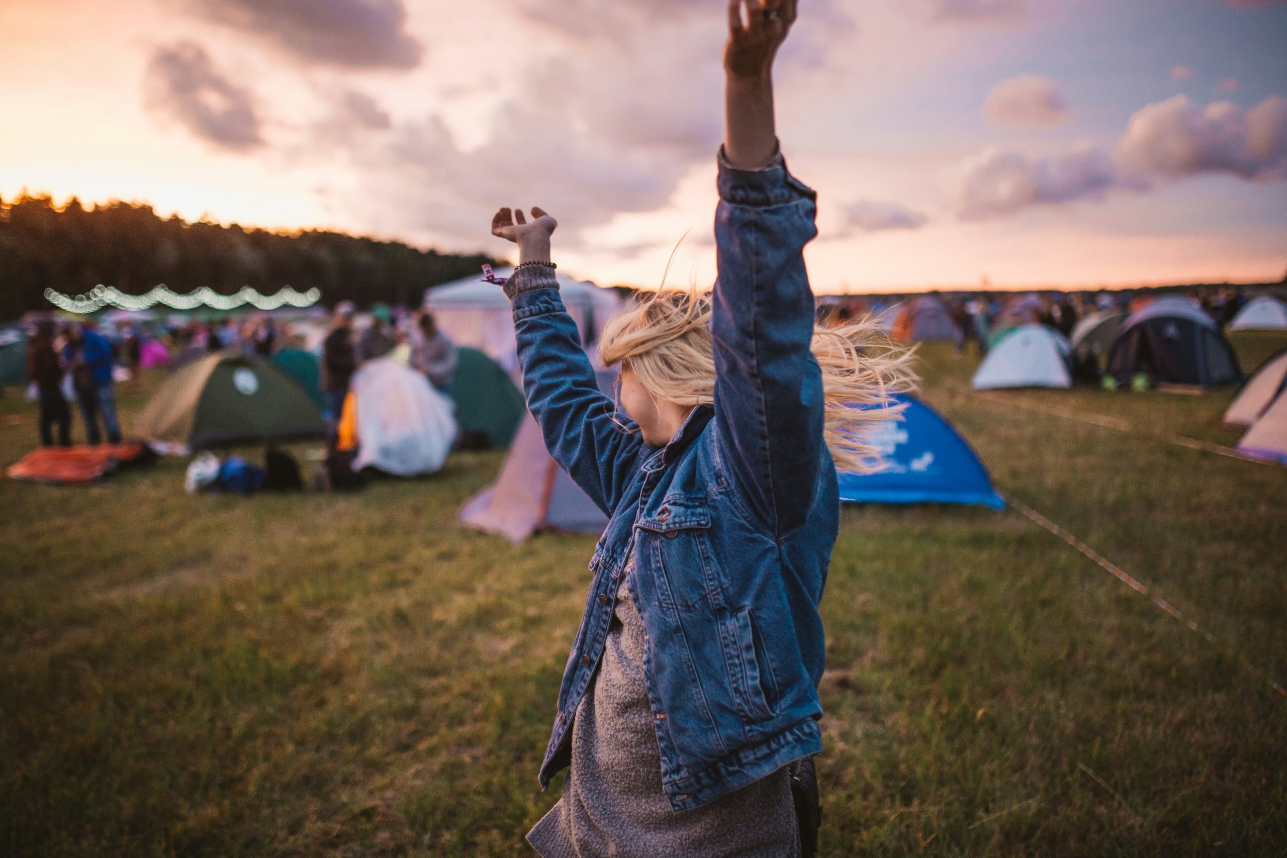 A woman enjoying a music festival, dancing amongst the tents.