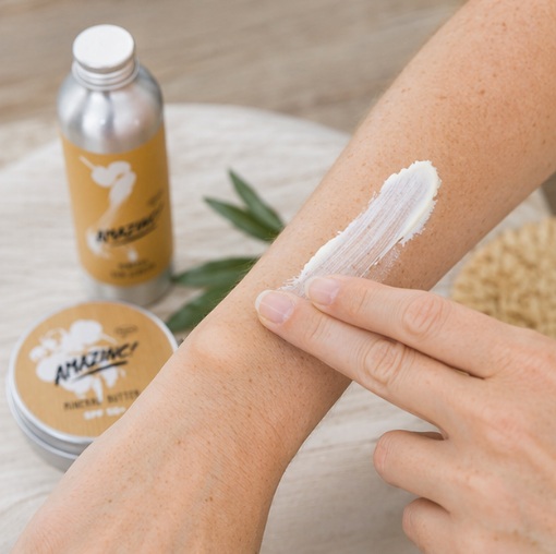 Some of the Amazinc! sun products available, presented on a neutral background, and someone applying cream onto their arm in the foreground.